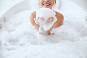 Cropped head portrait of pretty lady taking hydro luxurious bath with foam in spa resort
