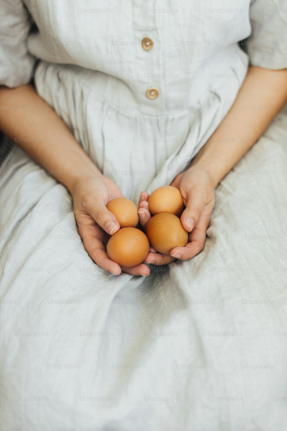 Happy Easter! Easter eggs in hands of woman in rustic linen dress. Woman holding natural easter eggs. Aesthetic eco holiday, stylish image