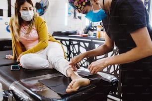 라틴 여성 문신 예술가는 페인트로 문신을하는 과정을 보여주고 멕시코 시티에서 파란색 멸균 장갑으로 작업합니다.
