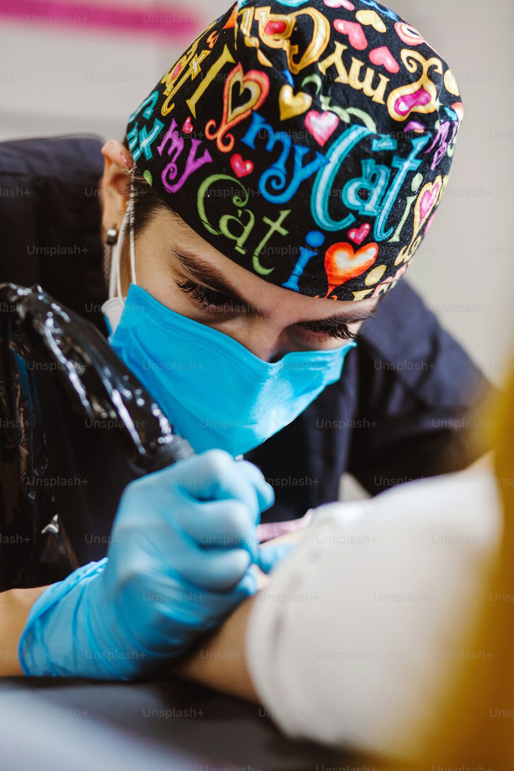 Lateinamerikanische Tätowiererin demonstriert den Prozess der Tätowierung mit Farbe und arbeitet in blauen sterilen Handschuhen in Mexiko-Stadt
