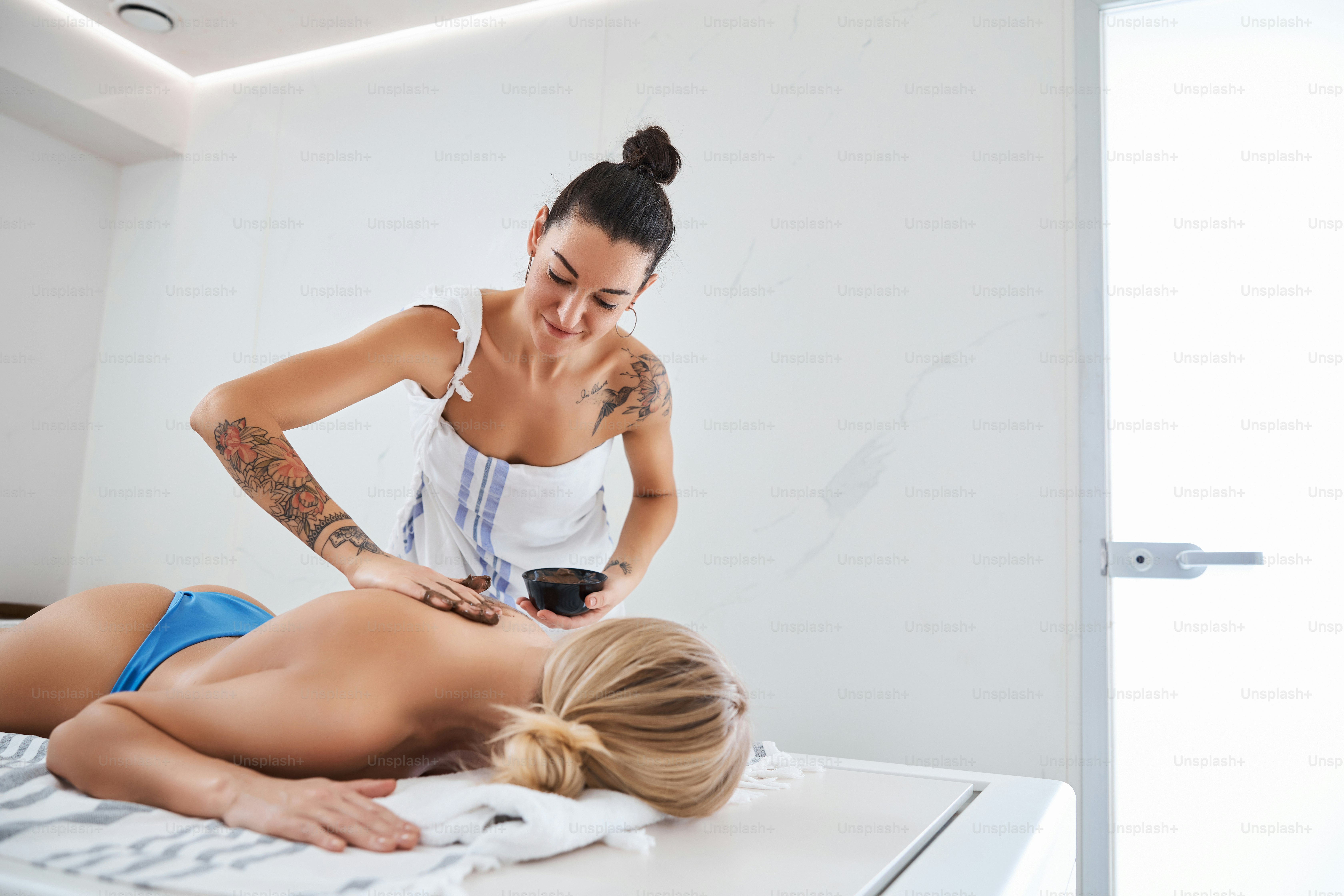 Close up portrait of dark hair hammam worker doing massage with chocolate on client back in room indoors