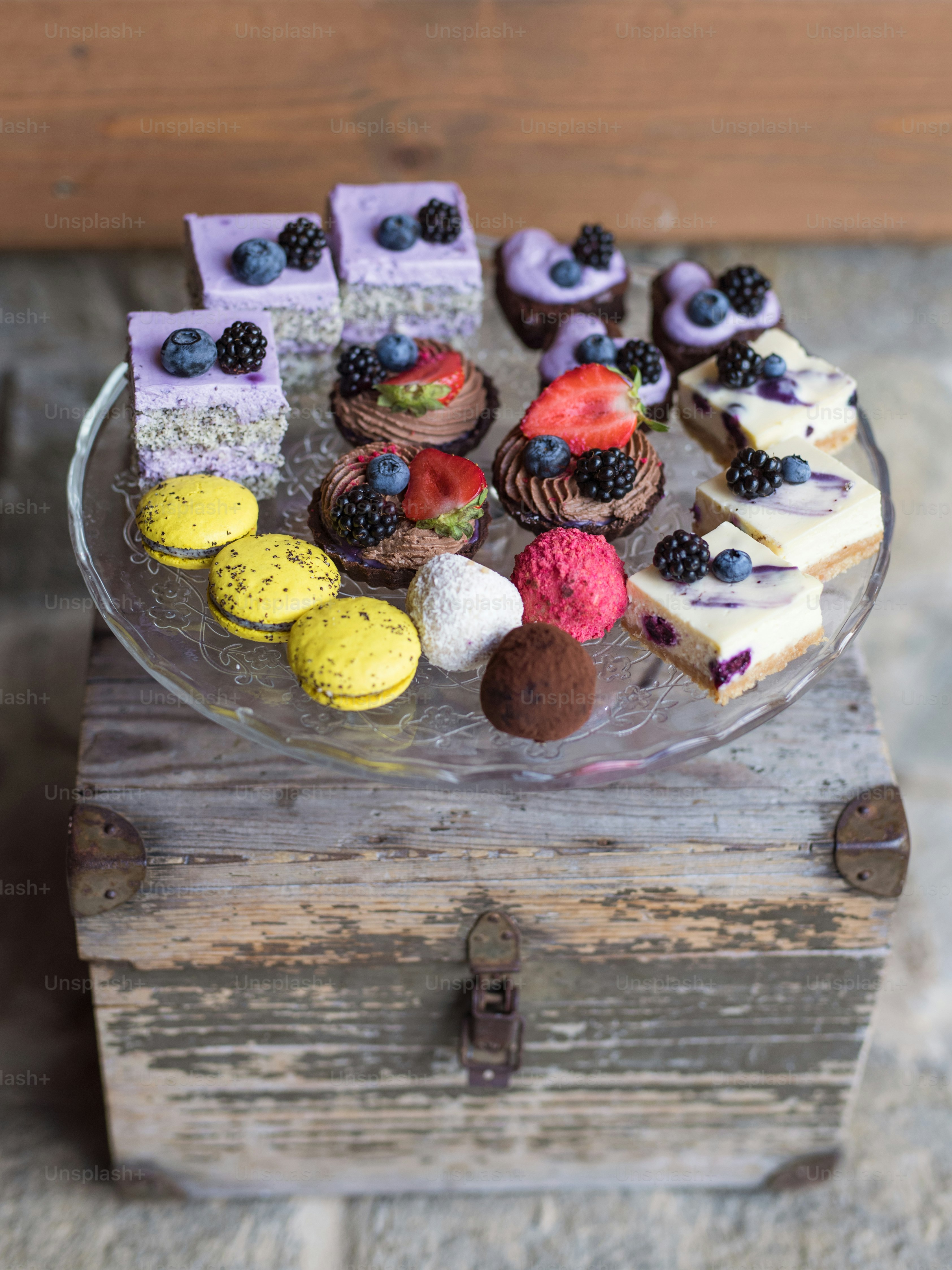 Selection of colorful and delicious cake desserts on a rusty wooden box ...