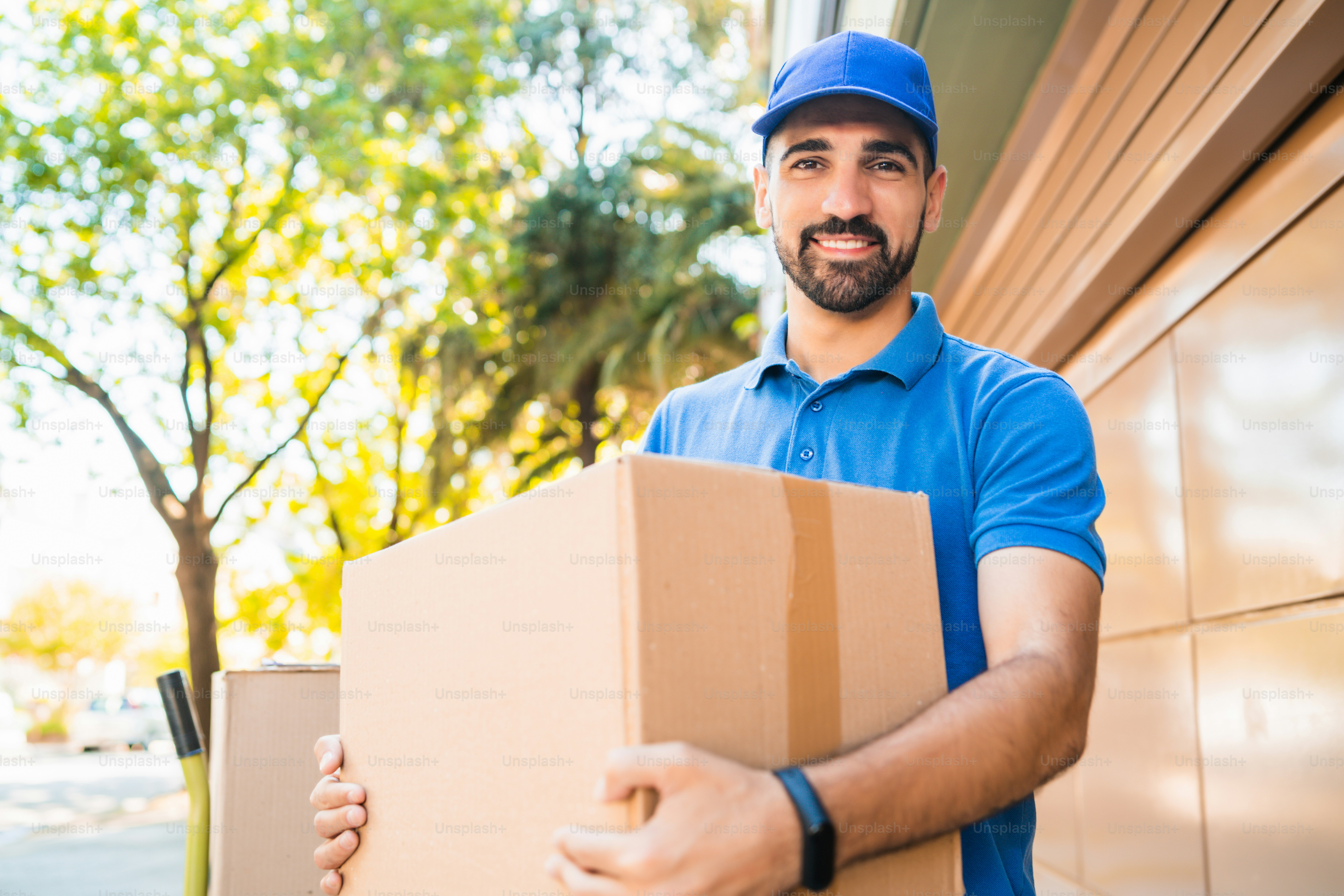Portrait of a delivery man courier with cardboard boxes in hands outdoors. Delivery and shipping concept.