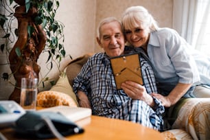 Happy moments. Adult parents admiring photo in frame and remembering youth. Stock photo