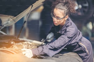 Mechanic repairing the motor or electric parts of a car in a garage"n