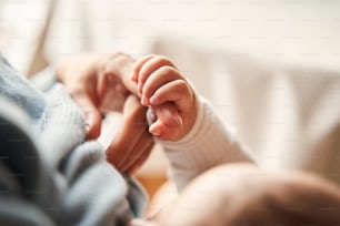 Tender moment. Close up view of the little newborn baby sleeping at the mother hands while holding her fingers with tender. Happy childhood concept