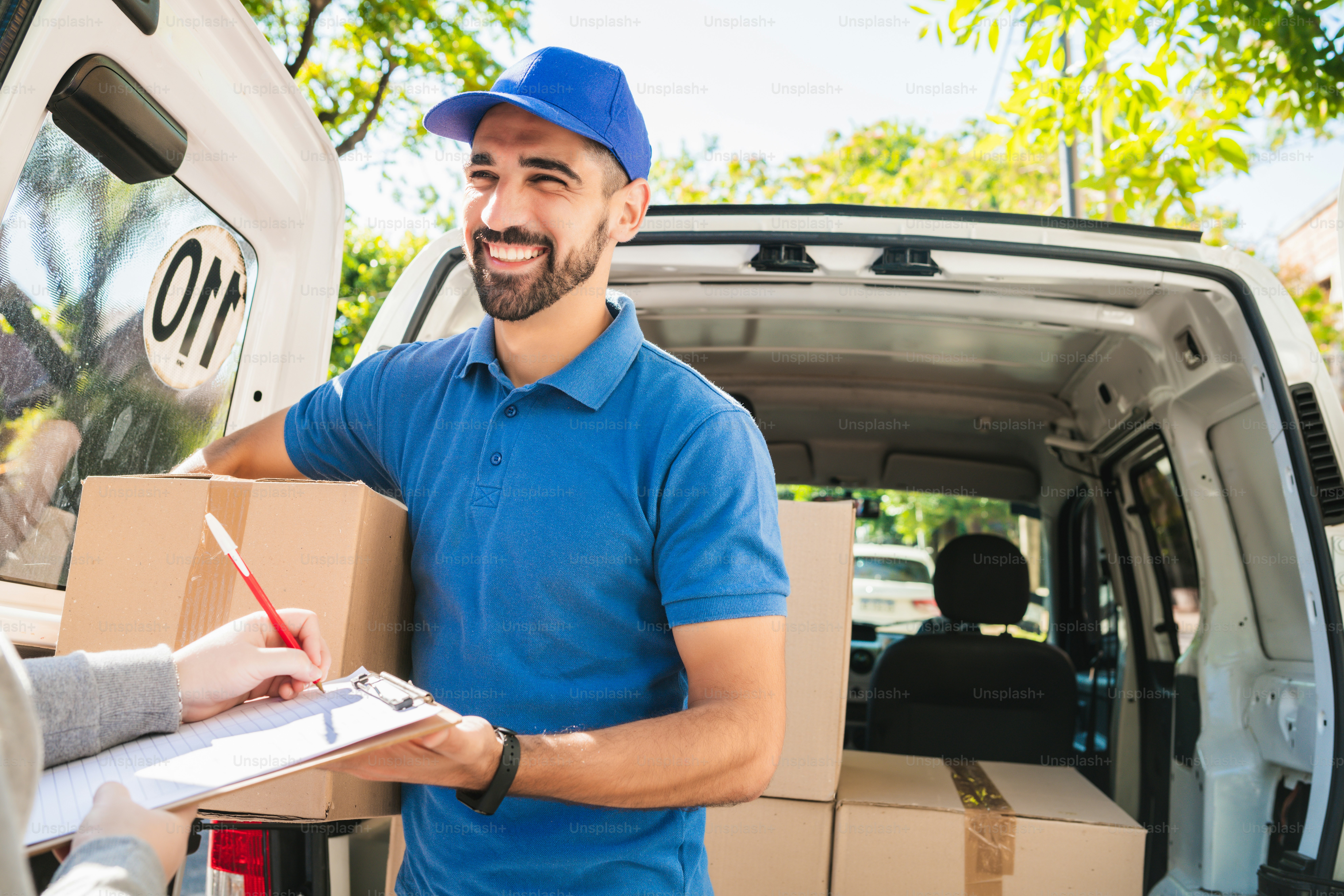 Portrait of a delivery man carrying packages while customer putting signature in clipboard. Delivery and shipping concept.