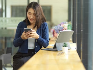 Retrato de una estudiante universitaria usando un teléfono inteligente mientras se relaja de hacer la tarea