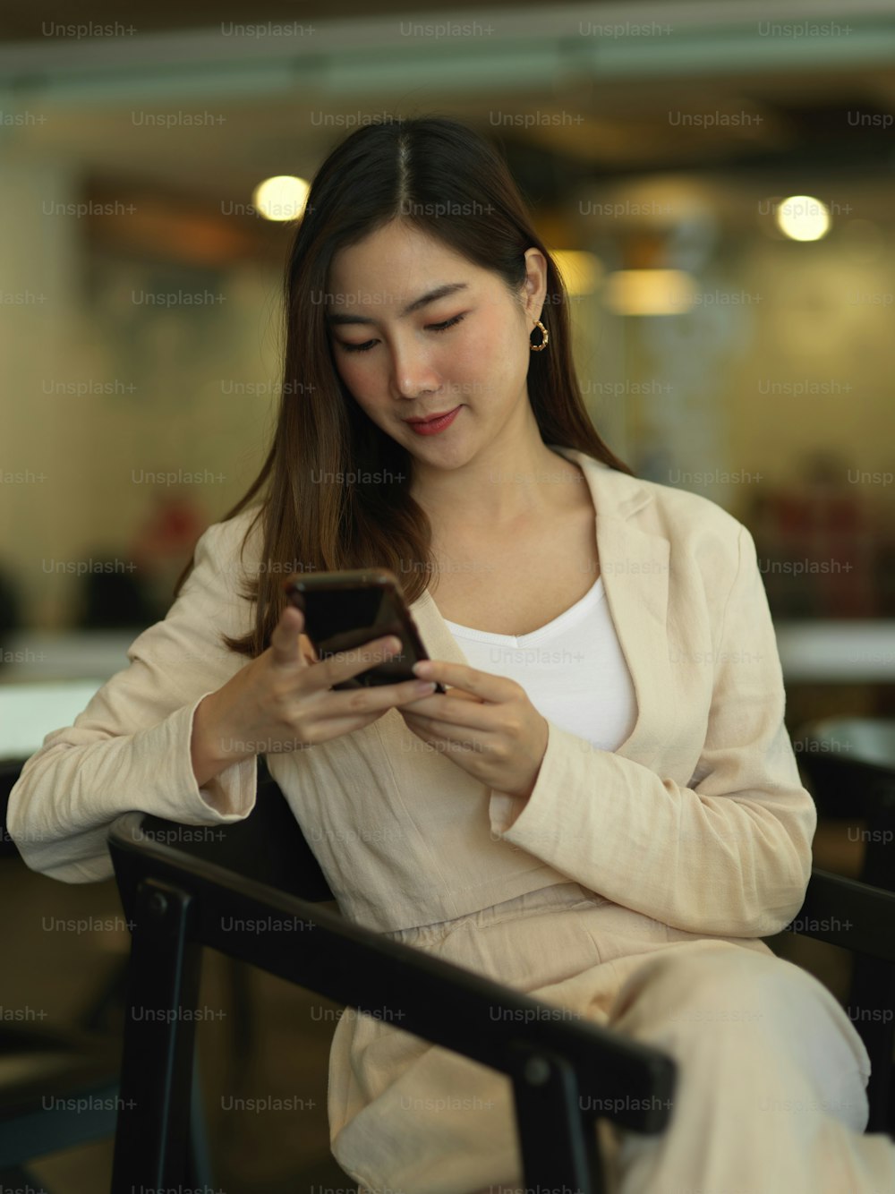 Portrait of businesswoman using smartphone while relaxed sitting in office room