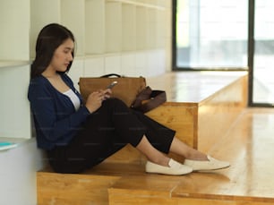 공동 작업 공간에 편안하게 앉아 스마트폰을 사용하는 여대생의 측면 모습