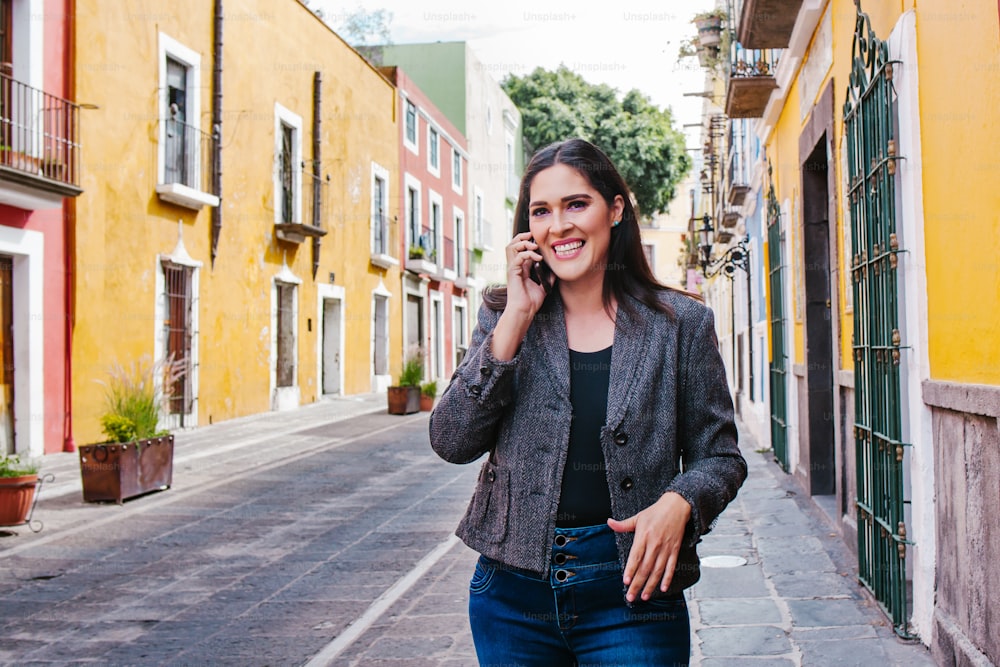 Donna d'affari messicana che parla al telefono mentre cammina in una città dell'America Latina