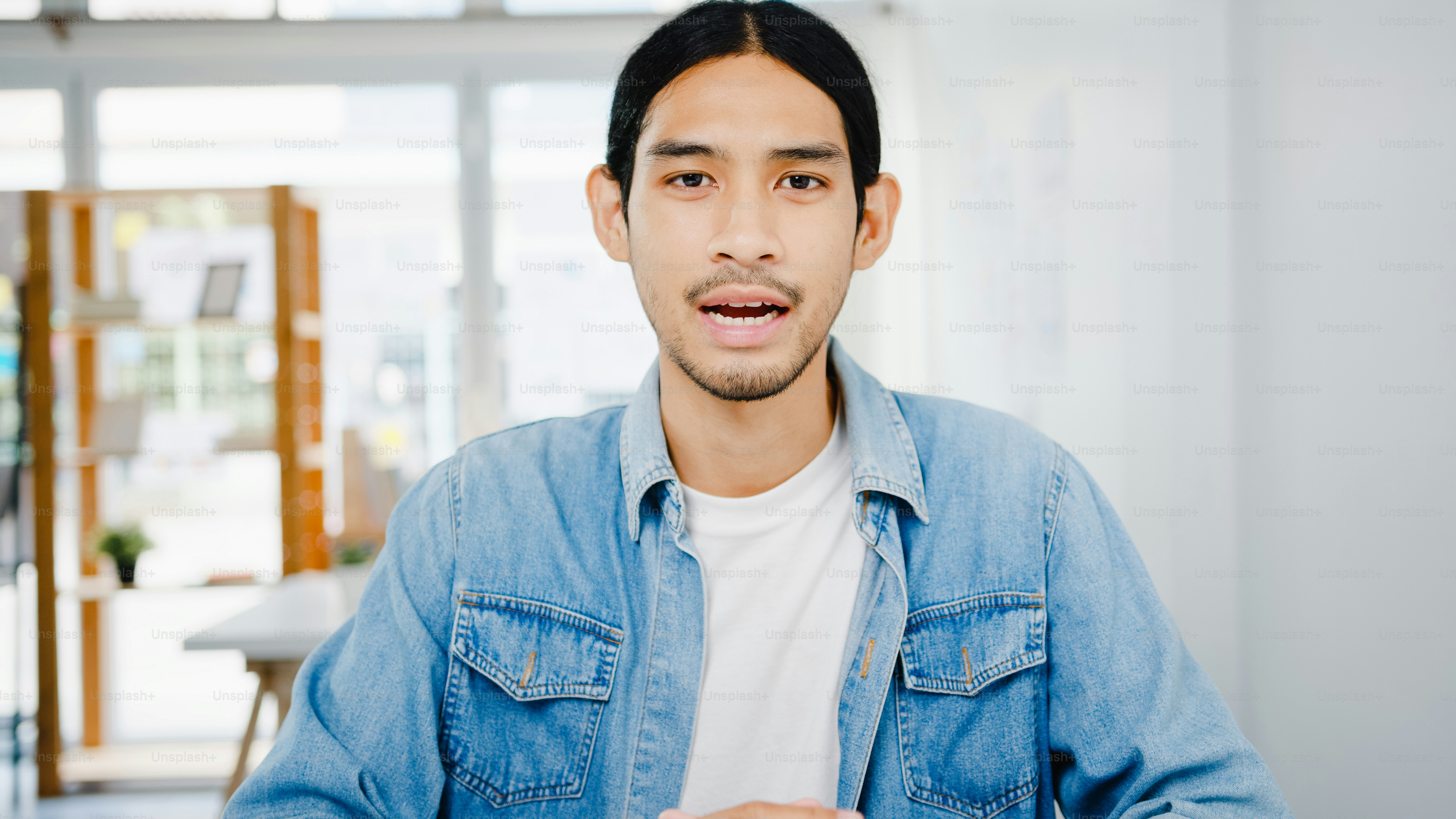 Uomo d'affari asiatico distanziamento sociale in una nuova situazione normale per la prevenzione del virus guardando la presentazione della telecamera al collega sul piano in videochiamata mentre lavora in ufficio. Lo stile di vita dopo il coronavirus.