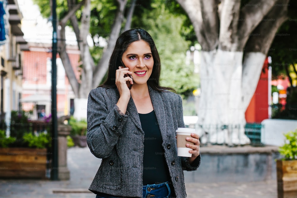 Mexican business woman talking by phone while she is walking in a Latin America city