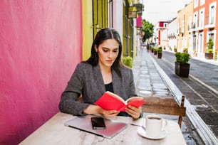 Mujer mexicana leyendo un libro en la terraza de una cafetería en una ciudad colonial de América Latina