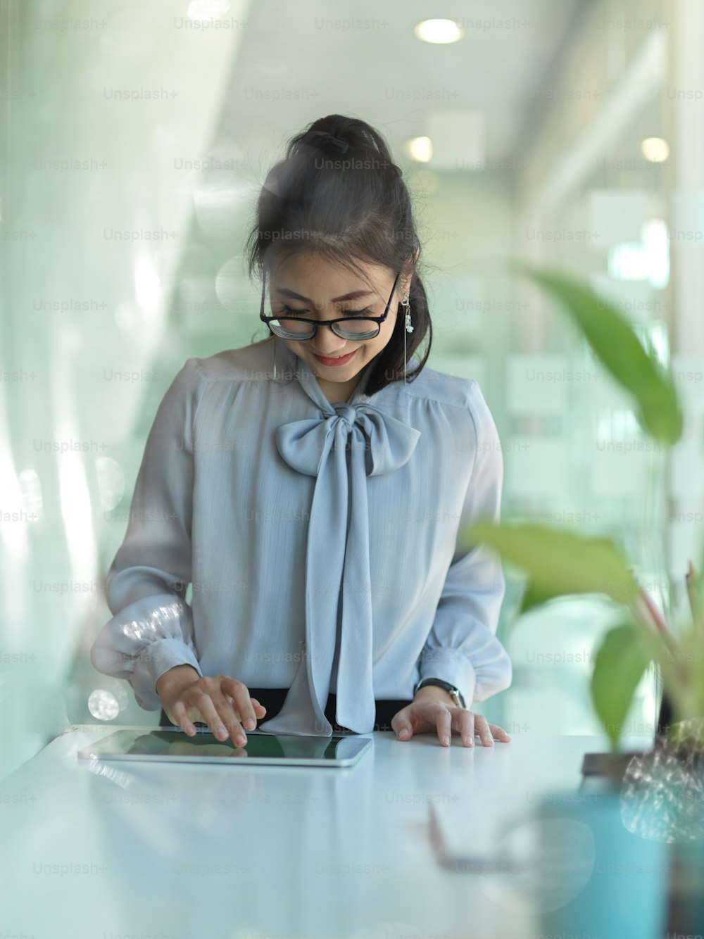 Ritratto di donna d'affari che tocca lo schermo della tavoletta digitale sul tavolo da lavoro nella stanza dell'ufficio