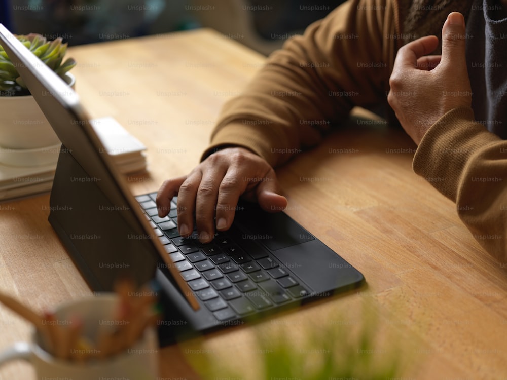 Seitenansicht eines Geschäftsmannes bei der Arbeit am digitalen Tablet auf einem Holztisch