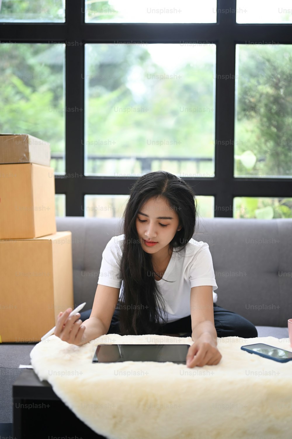 Portrait of start up small business entrepreneur SME or freelance woman working on digital tablet while sitting on couch.