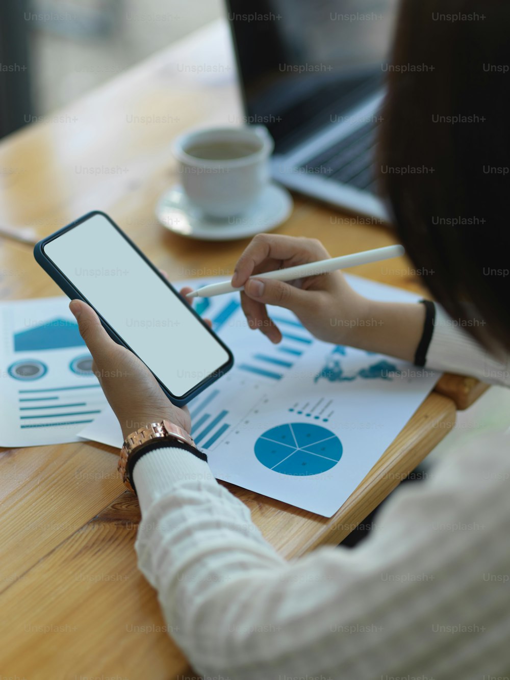 Plan recadré d’une femme d’affaires utilisant un smartphone tout en analysant un tableau d’affaires dans un bureau
