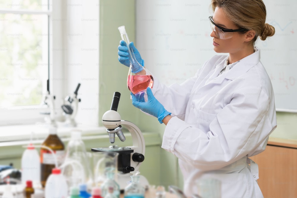 Un scientifique inspecte une substance à l’intérieur de la fiole dans un laboratoire pendant des travaux de recherche.