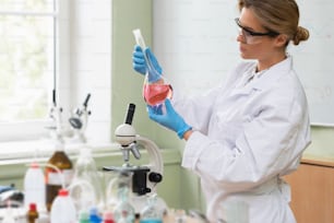 Scientist inspecting substance inside the flask in a laboratory during research work.