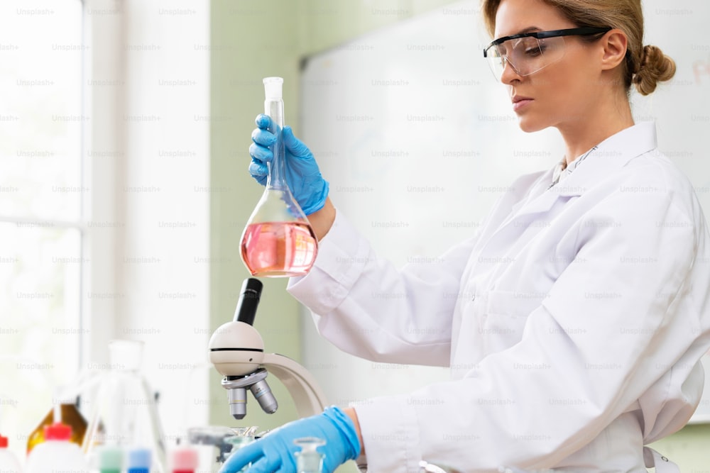 Scientist inspecting substance inside the flask in a laboratory during research work.