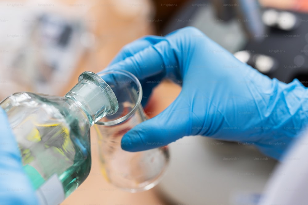 Wissenschaftler gießt während der Forschungsarbeit in einem Labor Substanz von einem Kolben in einen anderen
