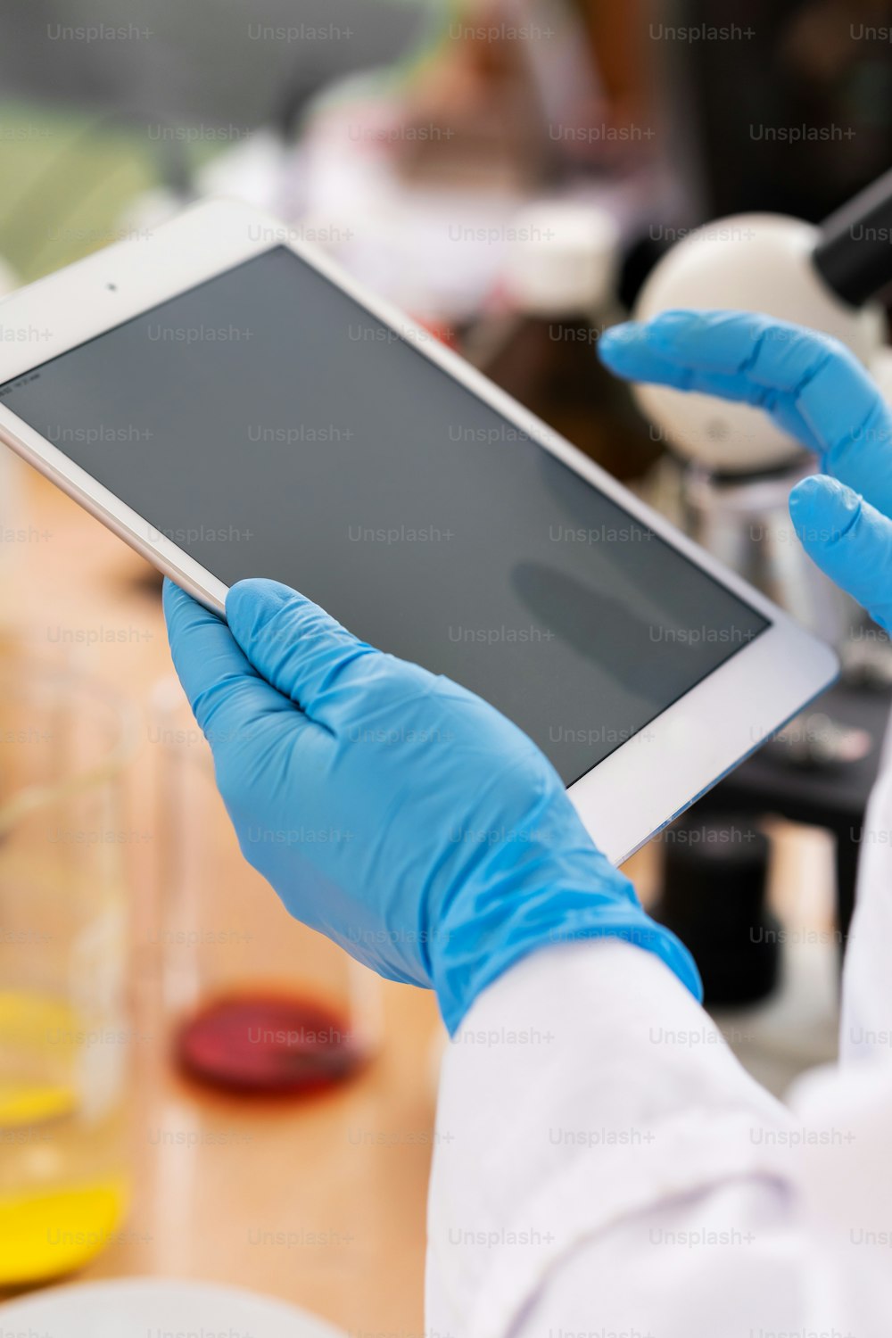 Nahaufnahme der Hände von Wissenschaftlern in den Latexhandschuhen mit einem Tablet-PC