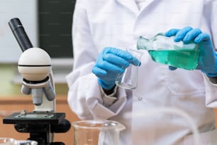 Científico vertiendo sustancia de un matraz a otro en un laboratorio durante un trabajo de investigación