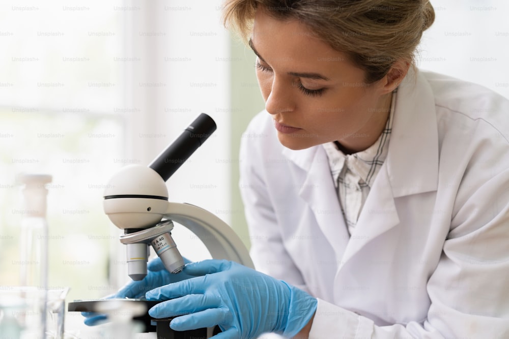 Une femme scientifique utilise un microscope dans un laboratoire pendant des travaux de recherche