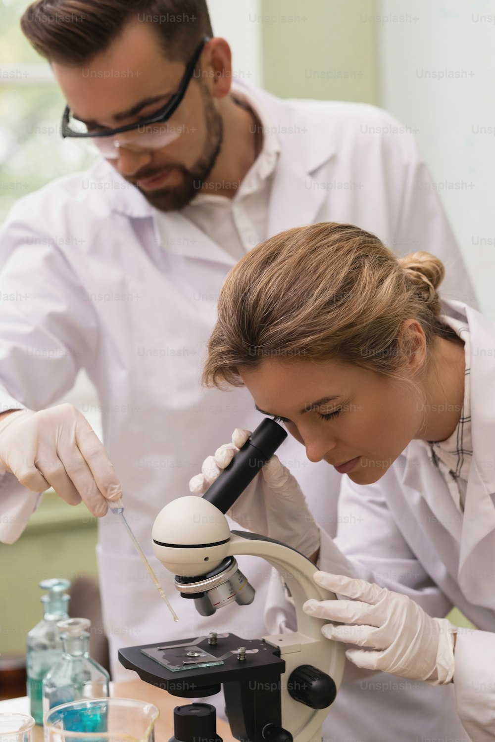 Two scientist colleagues are using microscope during research work in a laboratory