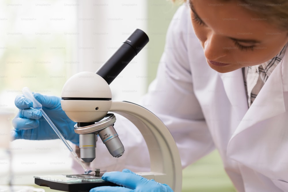 Une femme scientifique utilise un microscope dans un laboratoire pendant des travaux de recherche