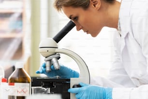 La scienziata sta usando il microscopio in un laboratorio durante il lavoro di ricerca