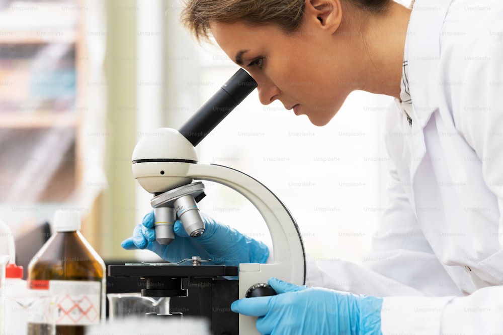 여성 과학자가 연구 작업 중 실험실에서 현미경을 사용하고 있다