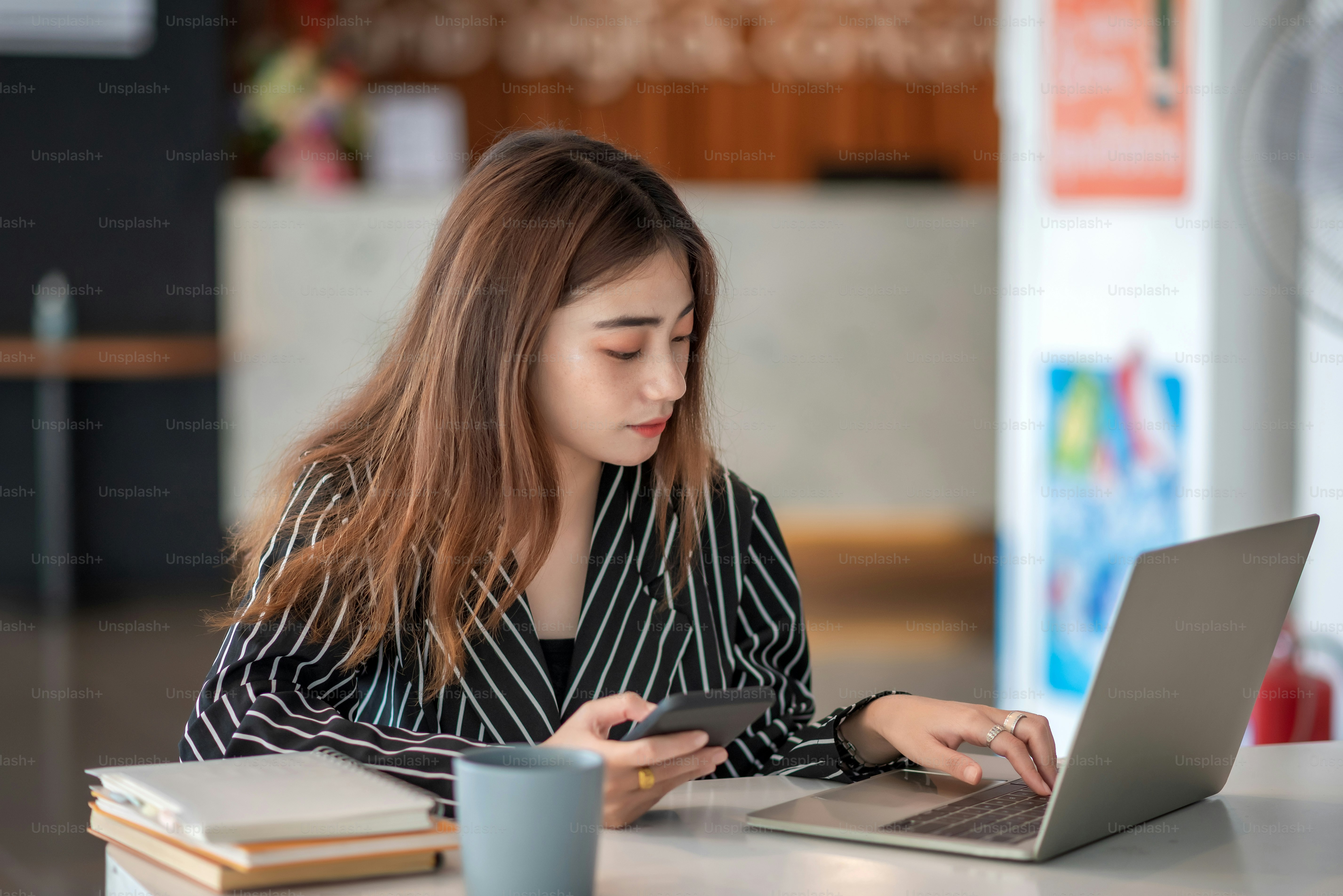 Wanita bisnis muda Asia cantik menawan tersenyum dan menggunakan komputer laptop di kantor modern.