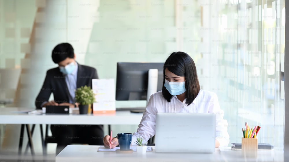 Businesspeople wearing protective mask working in modern office.