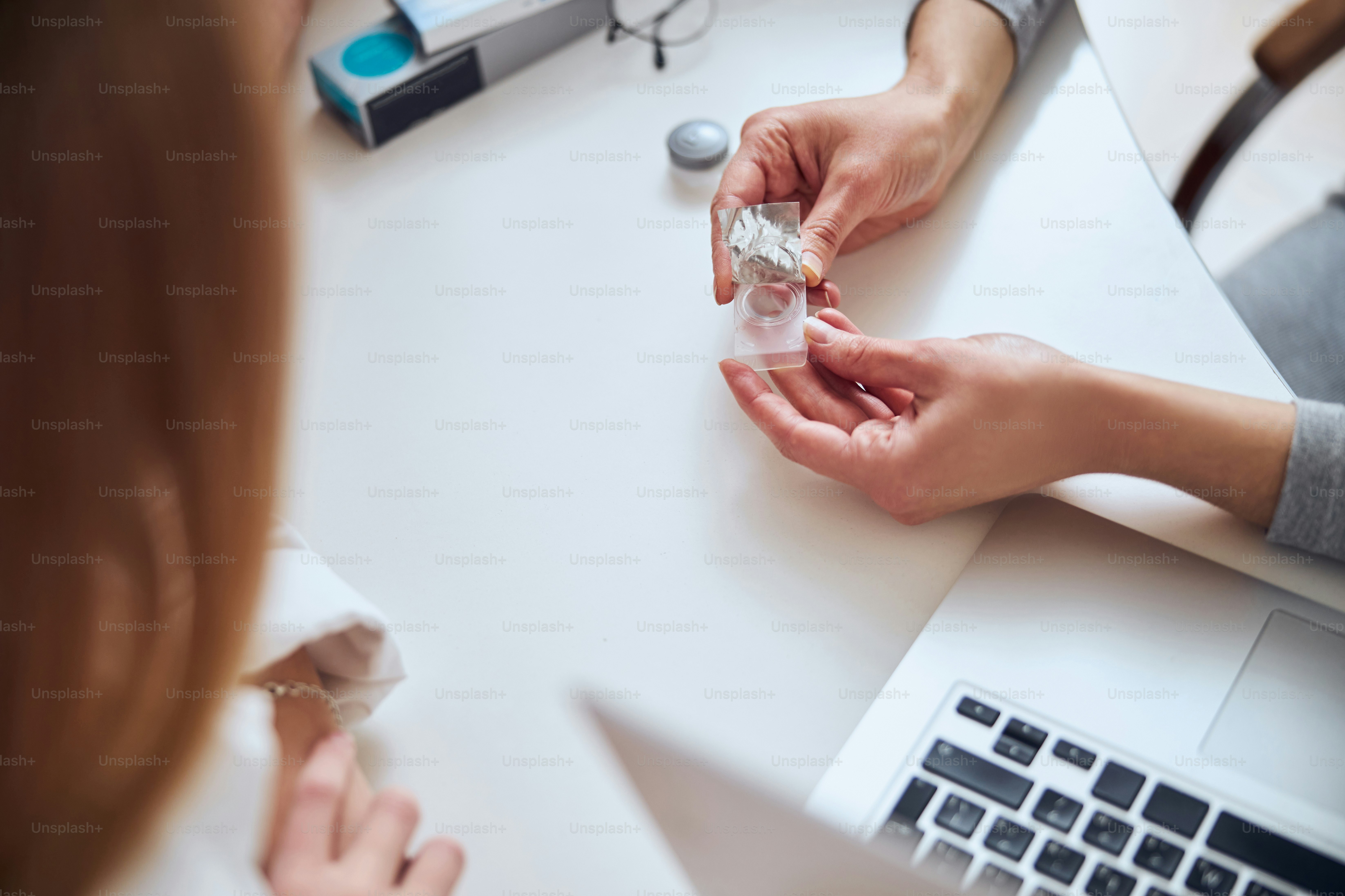 Fokussiertes Bild einer Frau mit Augenlinse über dem weißen Schreibtisch in der Optikerklinik