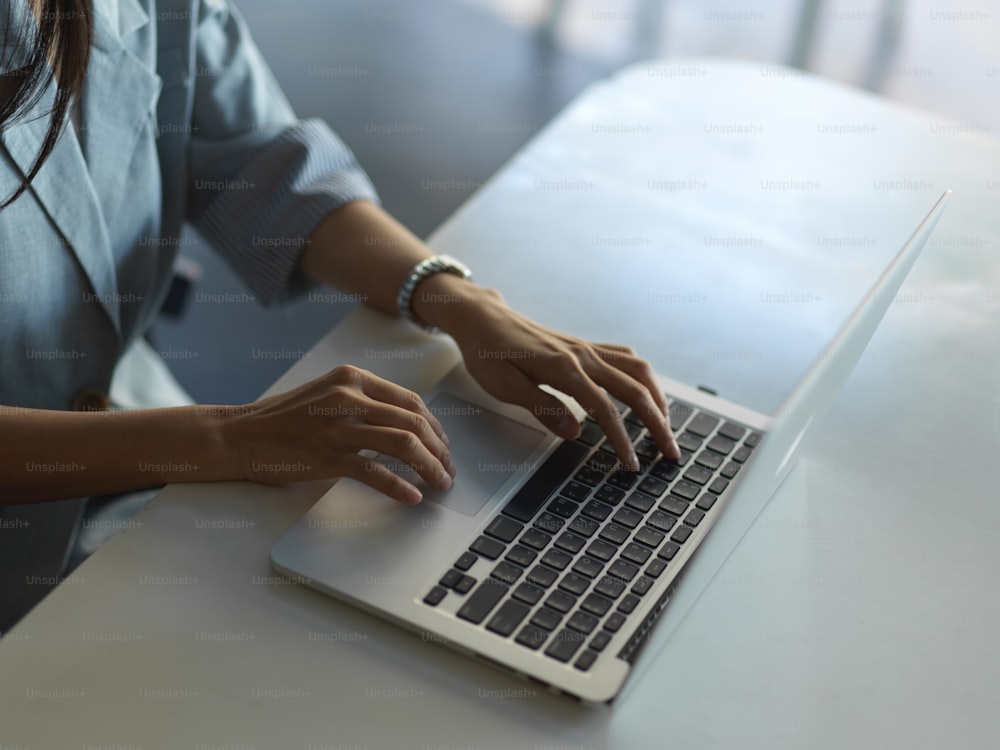 テーブルの上のノートパソコンのキーボードでタイピングする女性の手のトリミングショット