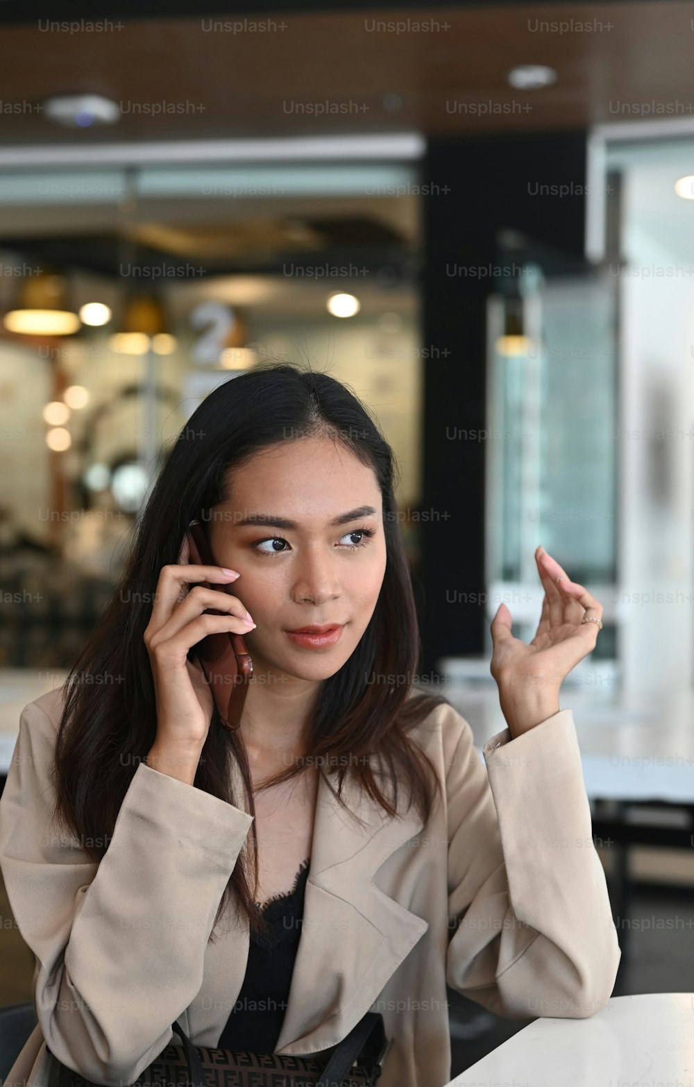 Portrait of cheerful businesswoman talking on mobile phone while sitting in office.