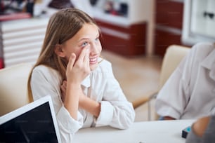 Close up side view portrait of beautiful smiling teenager girl choosing and trying lens of poor and blurred vision