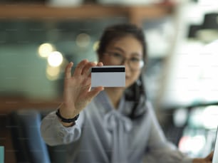 Close up view of businesswoman showing credit card in blurred background