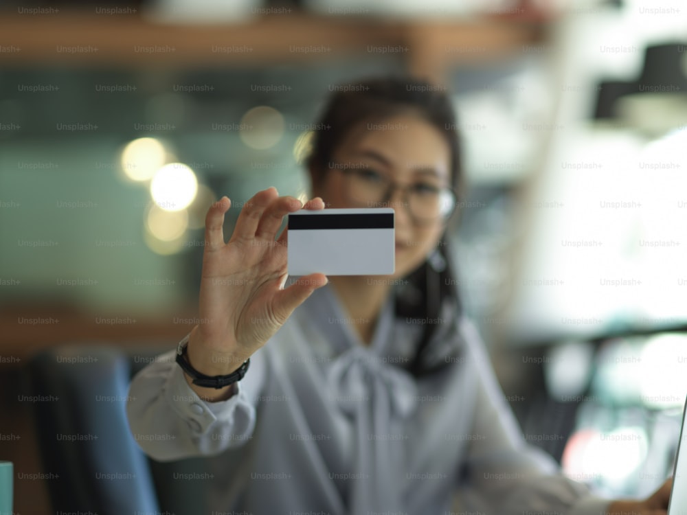 Close up view of businesswoman showing credit card in blurred background