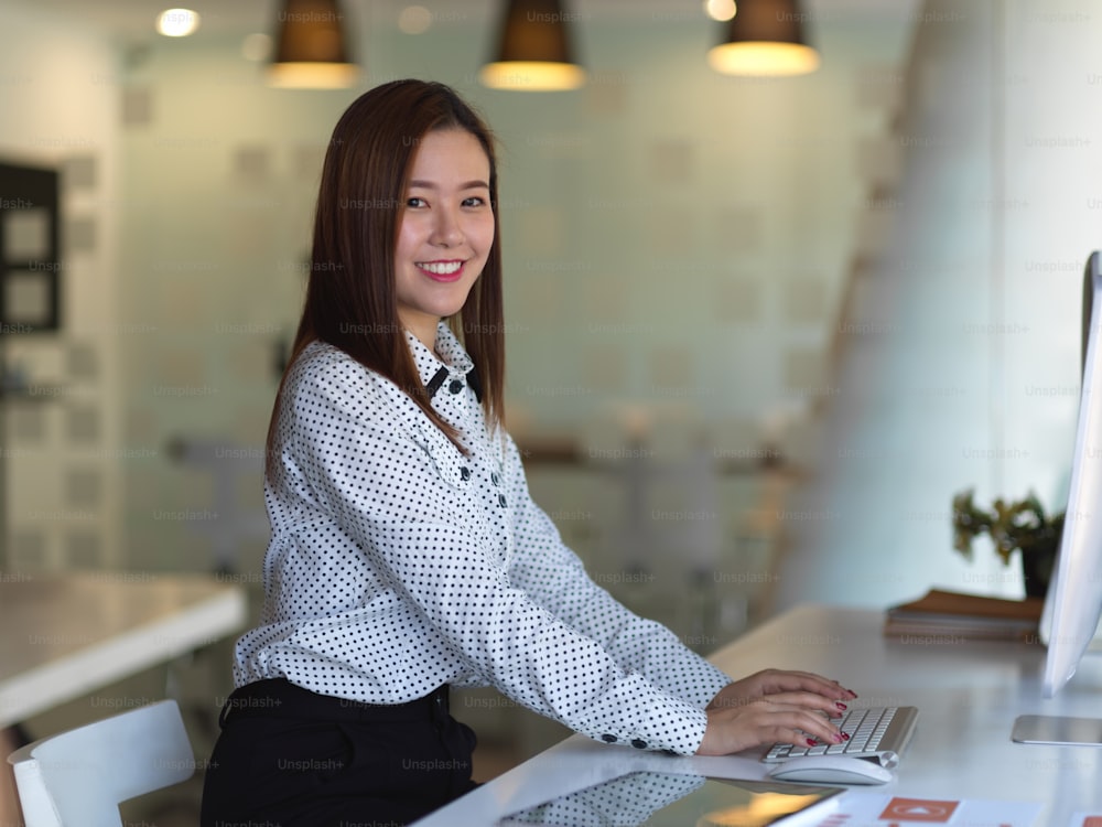 Side view of female office worker smiling to camera while working at workplace