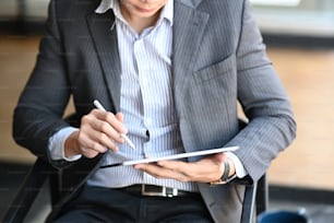 Cropped shot of businessman sitting on comfortable chair and using smart phone.