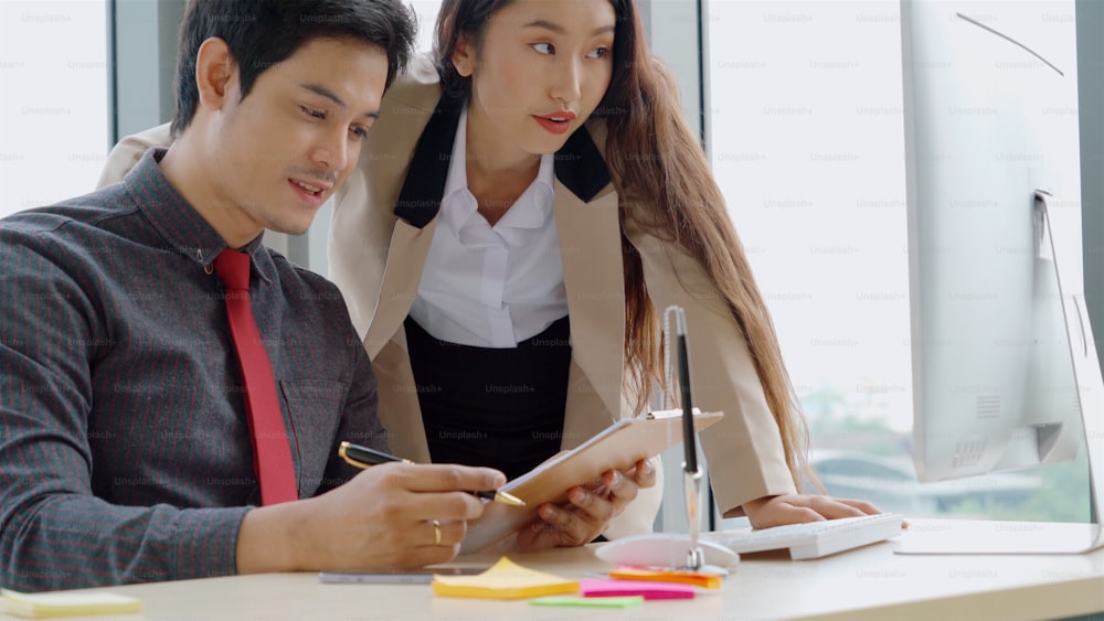 Two business people talk project strategy at office meeting room. Businessman discuss project planning with colleague at modern workplace while having conversation and advice on financial data report.