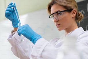 Un scientifique utilise un compte-gouttes et un tube à essai dans un laboratoire pendant des travaux de recherche.