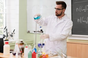 Uno scienziato sta versando sostanza nel condensatore in un laboratorio durante il lavoro di ricerca