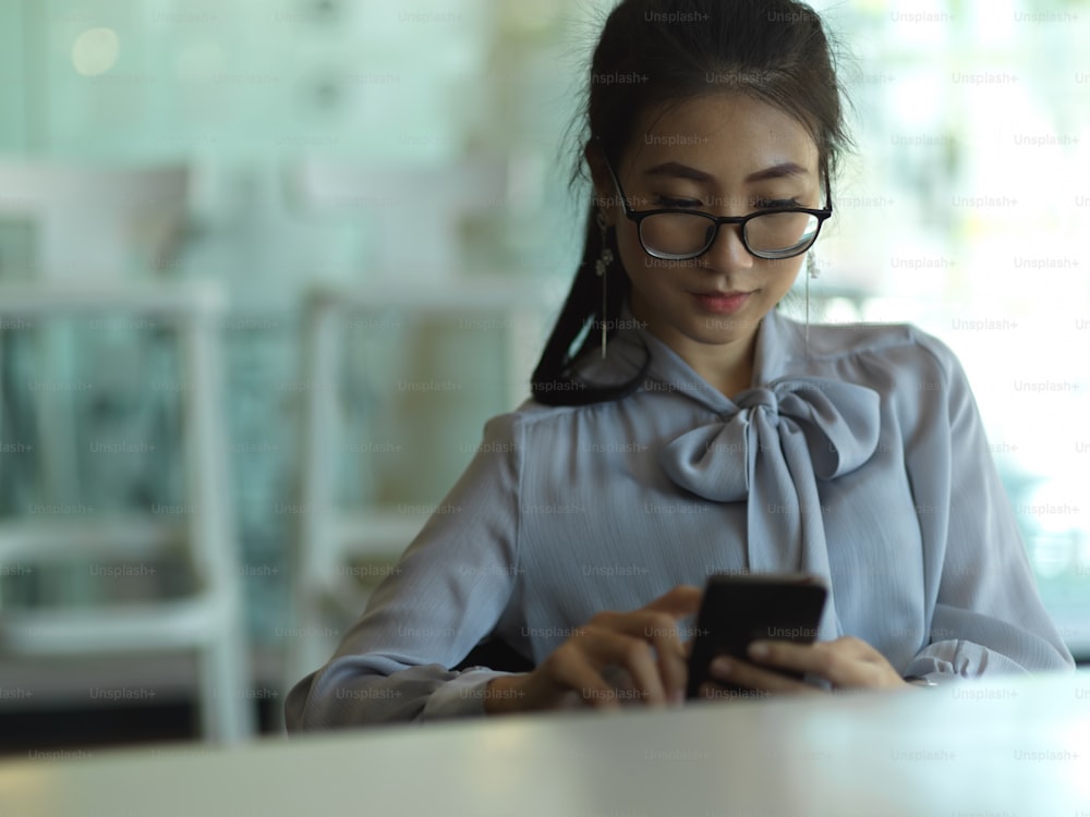 Portrait of businesswoman relaxing with smartphone while sitting in office room