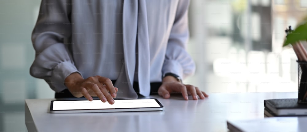 Cropped shot of businesswoman hand typing on screen of digital tablet at her office desk.