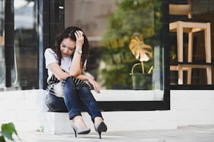 Mujer emprendedora de una pequeña empresa que se siente estresada debido a las condiciones económicas mientras está sentada frente a su cafetería.