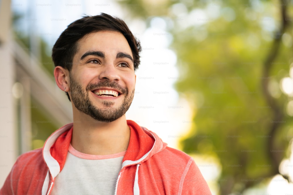 Close-up of young man smiling while standing outdoors at the street. Urban and lifestyle concept.
